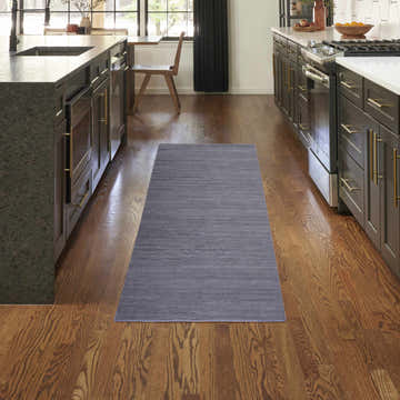 Modern kitchen with Nourison Essentials Navy runner rug between dark wood cabinets and hardwood floors.