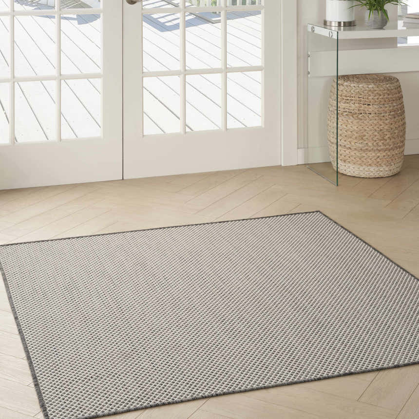 Light-filled room with herringbone floors and a Nourison Courtyard Ivory Charcoal rug in a modern, neutral space.