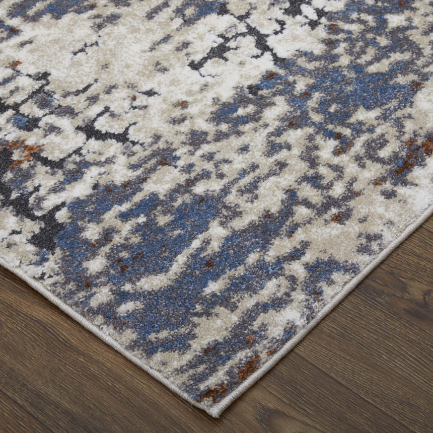 Close-up of the Feizy Gilmore rug, ivory, blue, and gray abstract pattern on a wood floor. Corner