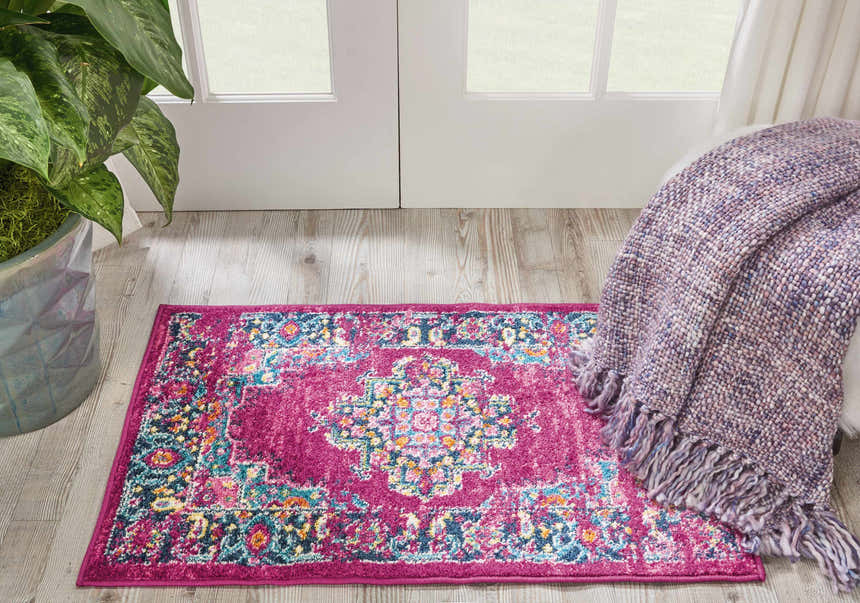 Entryway with Nourison Passion Fuchsia rug, wood floor, white door, potted plant, and a cozy purple throw blanket.