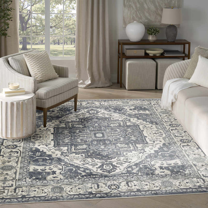 Living room scene with a Nourison Quarry Navy Ivory Vintage Area Rug, sofa, chair, and natural light.
