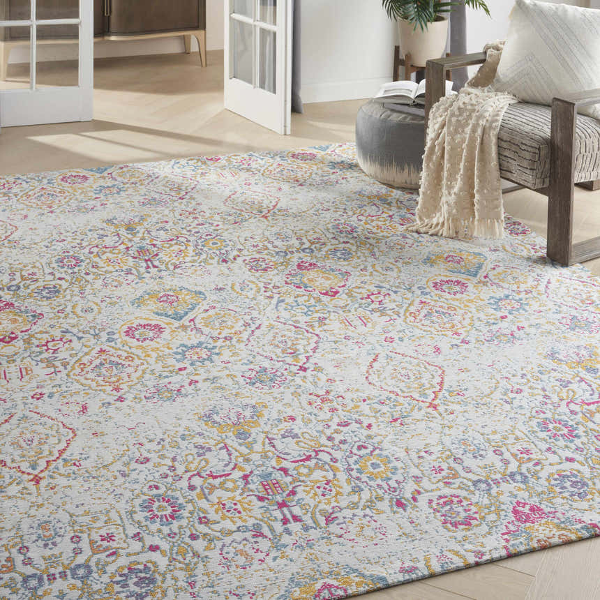 Living room scene with Nourison Damask Multicolor Bohemian rug, gray chair, ottoman, and light wood floors.