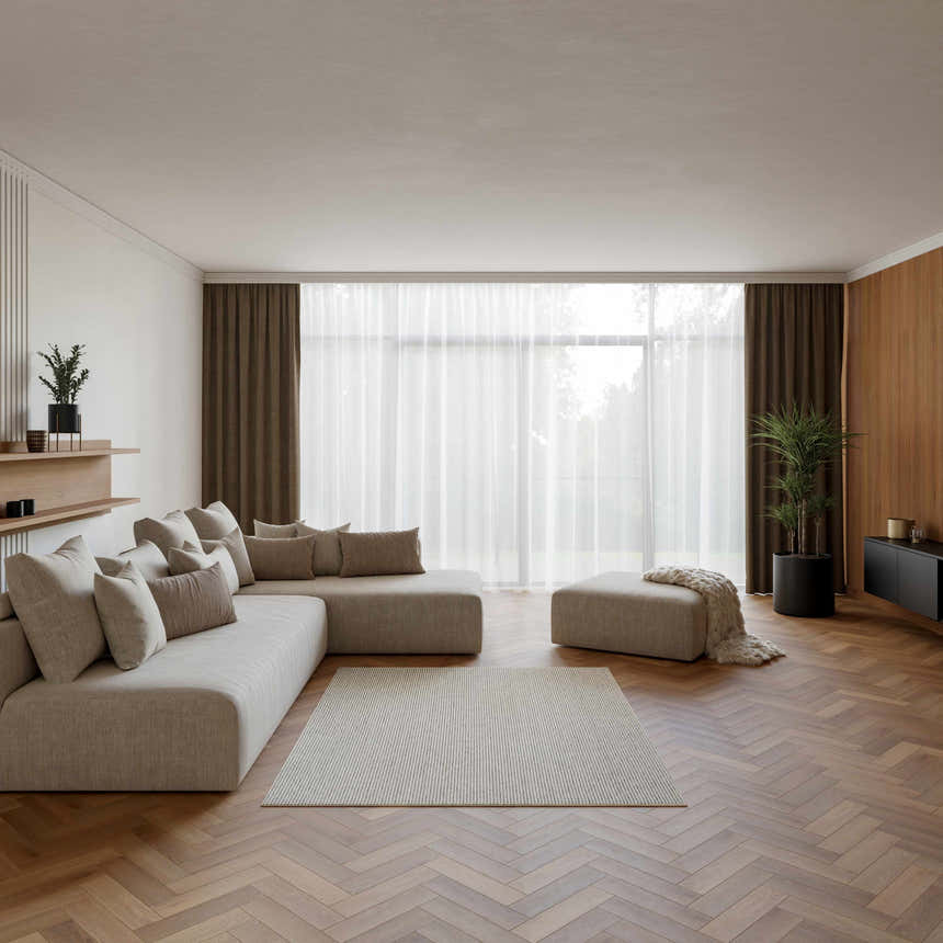 Living room scene with a Nourison Natural Texture Ivory Grey Farmhouse rug, sectional sofa, and herringbone wood floors.