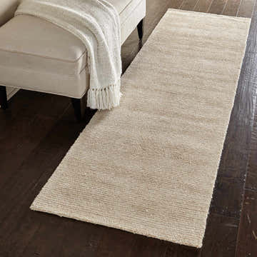 Beige Nourison Weston Linen runner rug in a hallway with dark wood floors and a bench.