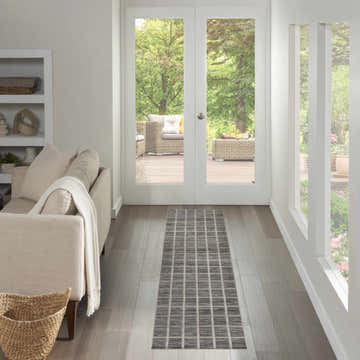 Hallway with a Nourison Serenity Home Grey Ivory rug, leading to a patio with wicker furniture and a garden view.