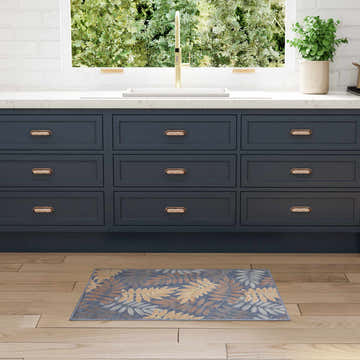 Blue rose Nourison Aloha rug in a kitchen with navy cabinets and wood floors.