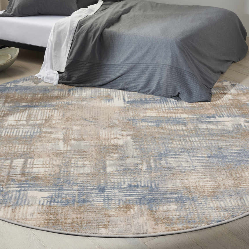 Modern bedroom scene with a round Calvin Klein CK950 Rush Blue Beige area rug under a gray bed.