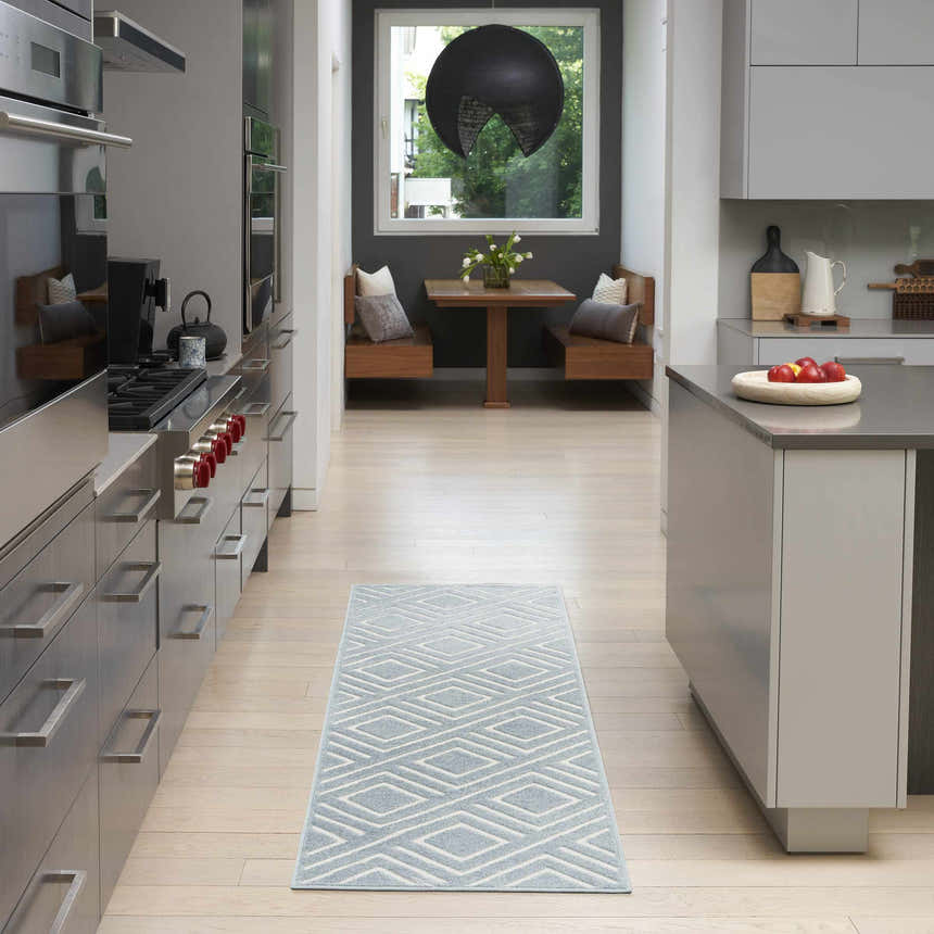 Modern kitchen with stainless steel appliances and Nourison Care Free Blue runner rug with geometric diamond pattern.
