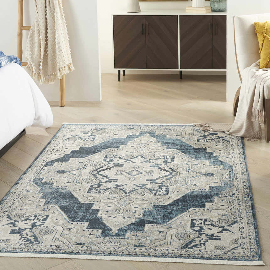 Bedroom scene with blue and gray Nourison Carina vintage rug, bed, wood floors, and modern cabinet.