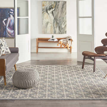 Living room scene with a grey Nourison Cozumel Farmhouse Area Rug, sofa, ottoman, bench, and art.