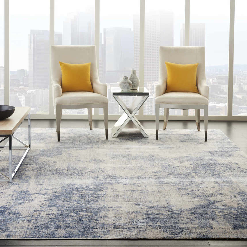 Modern living room with Nourison Silky Textures Ivory/Blue rug, chairs with yellow pillows, and city view.