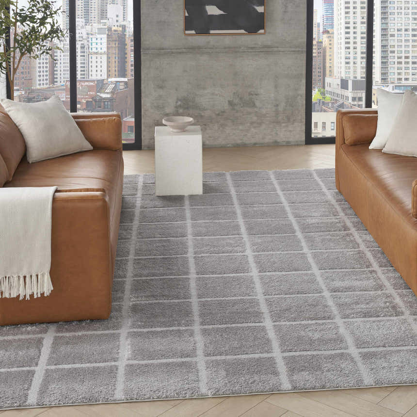 Modern living room with brown leather sofas and DKNY West End Ave Grey area rug with a geometric pattern.