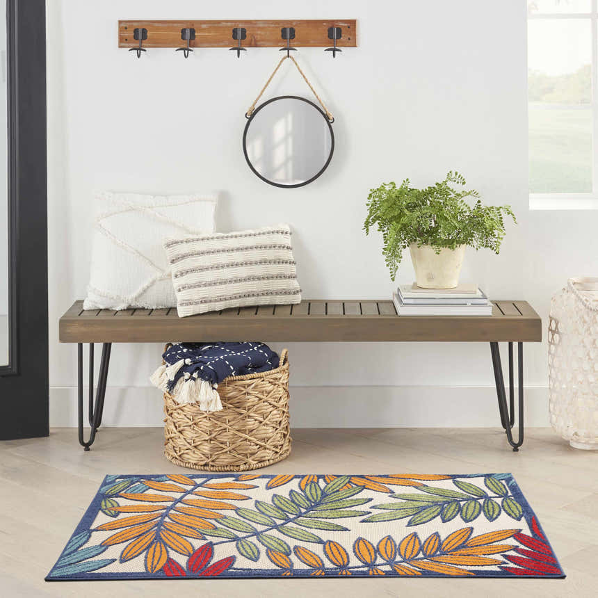 Entryway with wood bench, pillows, and Nourison Aloha Multicolor Tropical Area Rug with orange, green, and red leaves.
