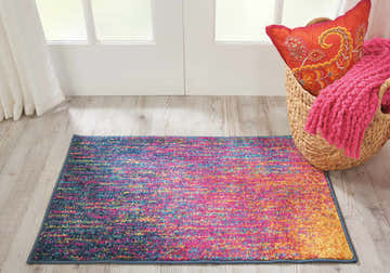 Entryway scene with a Nourison Passion Multicolor rug, basket with pink throw and orange pillow.