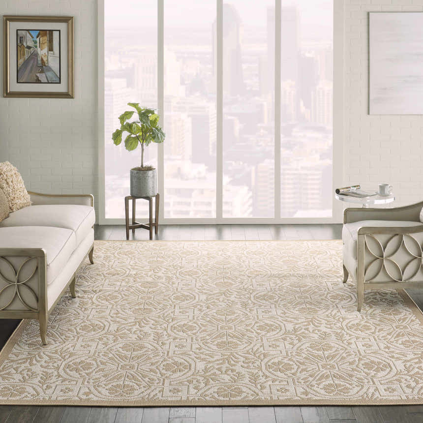 Living room scene with a Nourison Aruba Beige Cream Area Rug, cream sofa and chair, and city view.
