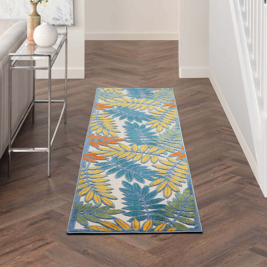 Hallway scene with Nourison Aloha Ivory Multicolor Tropical Area Rug, wood floors, and console table.