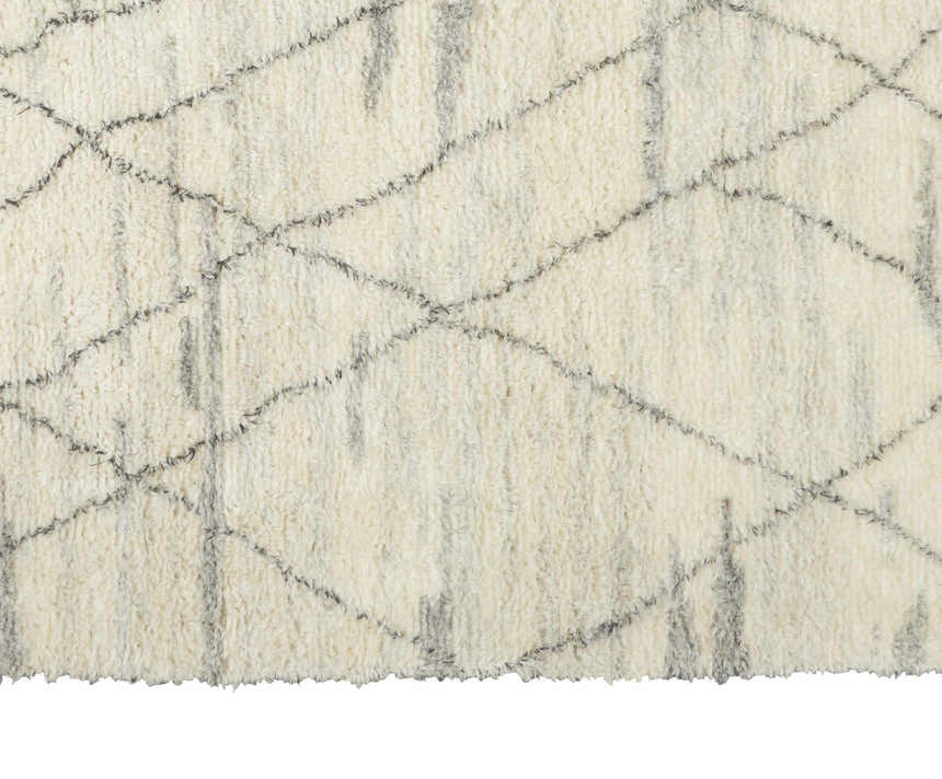 Close-up of the Calvin Klein San Antonio rug. Ivory shag rug with a chestnut Moroccan diamond pattern. Handmade wool texture.