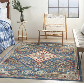 Farmhouse bedroom scene with the Nourison Karisma Blue Ivory area rug, wooden chair, and blue bedding.