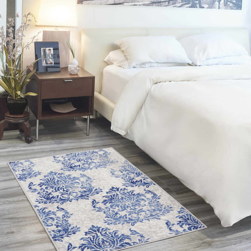 Farmhouse bedroom scene with Nourison Whimsicle Ivory Navy rug, white bedding, and wood nightstand.
