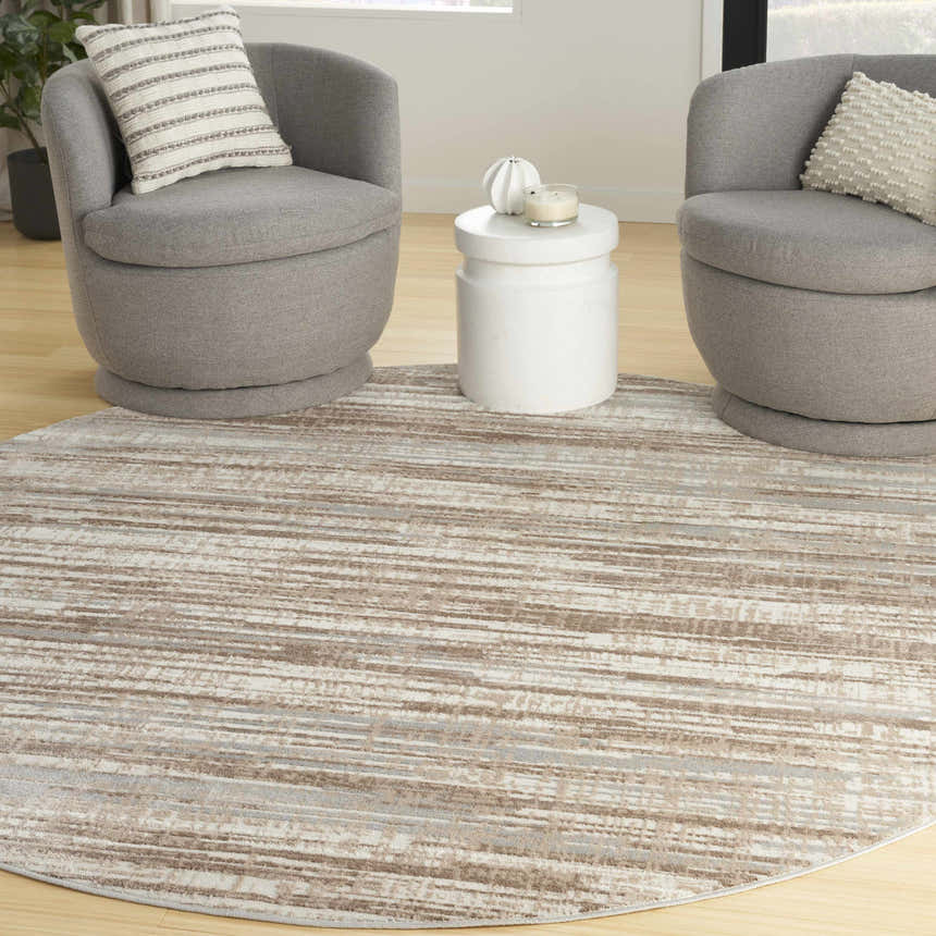 Modern living room scene with grey chairs and a round Nourison Elation Ivory Grey Area Rug.