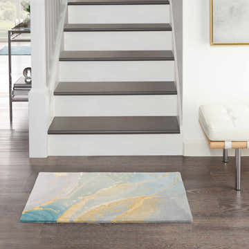 Entryway with Nourison Prismatic Grey Seafoam rug, wood floors, white stairs, and modern bench.