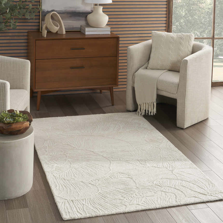 Modern living room with a Nourison Avra Ivory rug, wood dresser, and neutral armchairs.