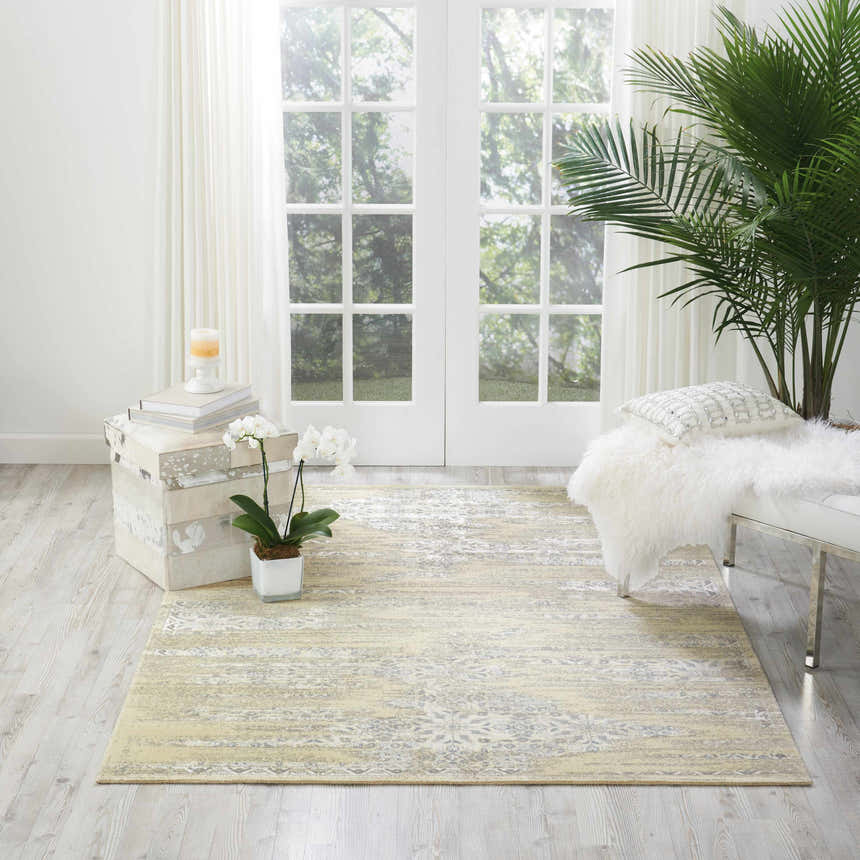 Bright sunroom with Nourison Luminance Bone Vintage rug, white bench, palm, and decorative chest.