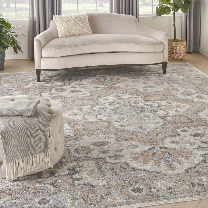 Living room scene with a Nourison Astra Silver Grey Vintage Rug, beige sofa, and ottoman.