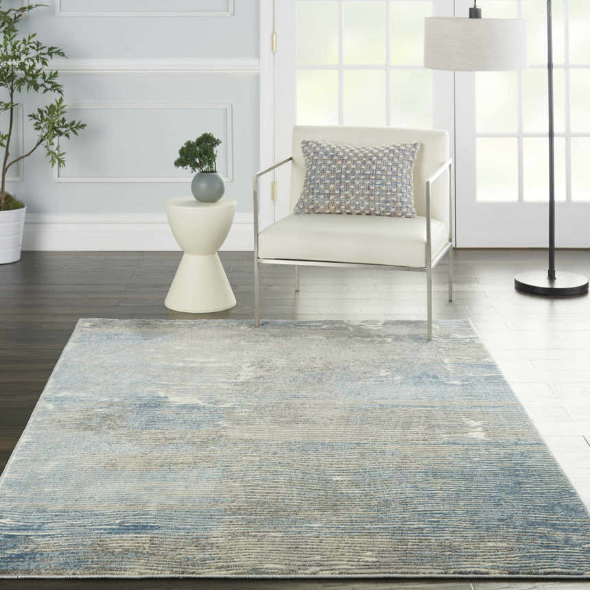 Modern living room with a Nourison Solace Ivory Grey Blue rug, chair, side table, and lamp.