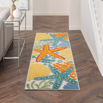 Hallway with Nourison Aloha runner rug. Coastal style with starfish and shells on a herringbone wood floor.