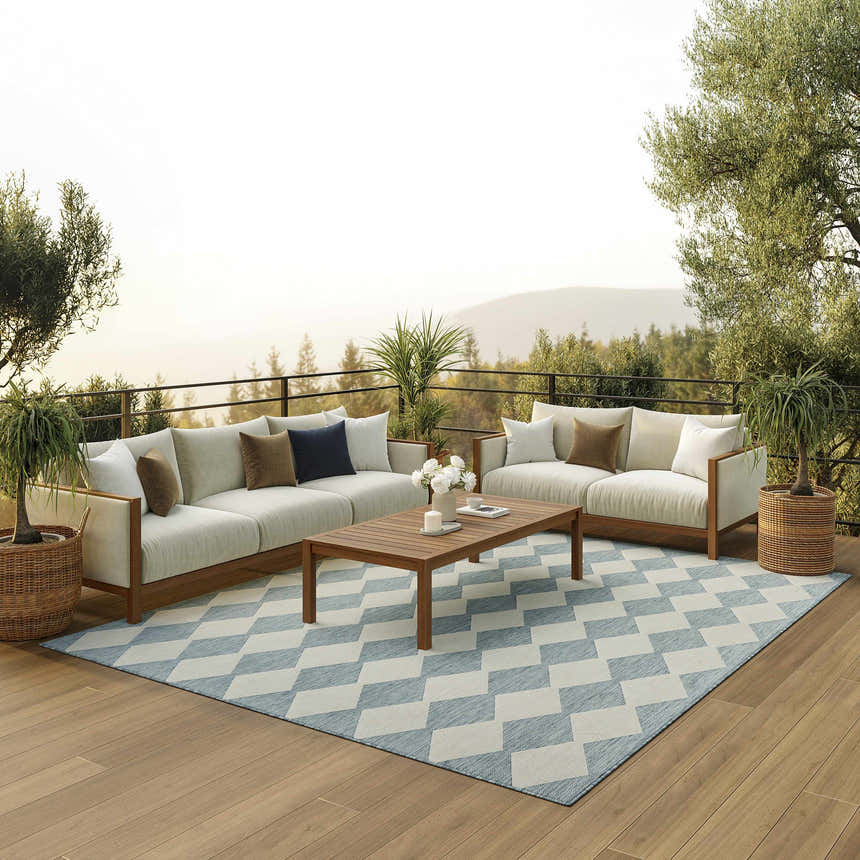 Outdoor patio scene with white sofas and aqua Nourison Positano rug with diamond pattern, wood floors and coffee table.