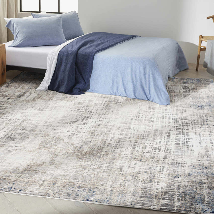 Modern bedroom with a Calvin Klein CK022 Infinity Blue Multicolor rug, blue bedding, and wood accents.
