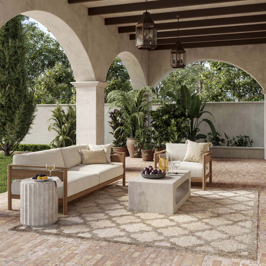 Outdoor patio with sofa, plants, and Nourison Easy Care Natural Beige Modern Area Rug.