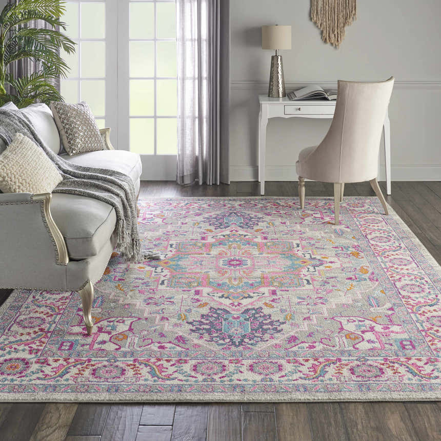 Living room scene with a Nourison Passion Light Grey Pink rug, sofa, desk, and chair. Bohemian style.
