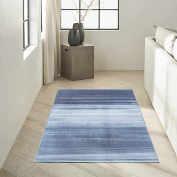 Modern living room with aqua Calvin Klein Launder rug. Striped rug on light wood floors, neutral sofa, and natural light.