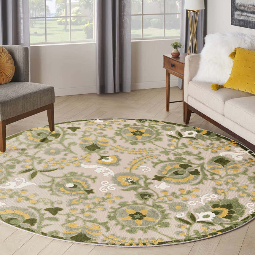 Living room with a round Nourison Aloha Ivory Green Outdoor Area Rug, gray chair, and neutral sofa.