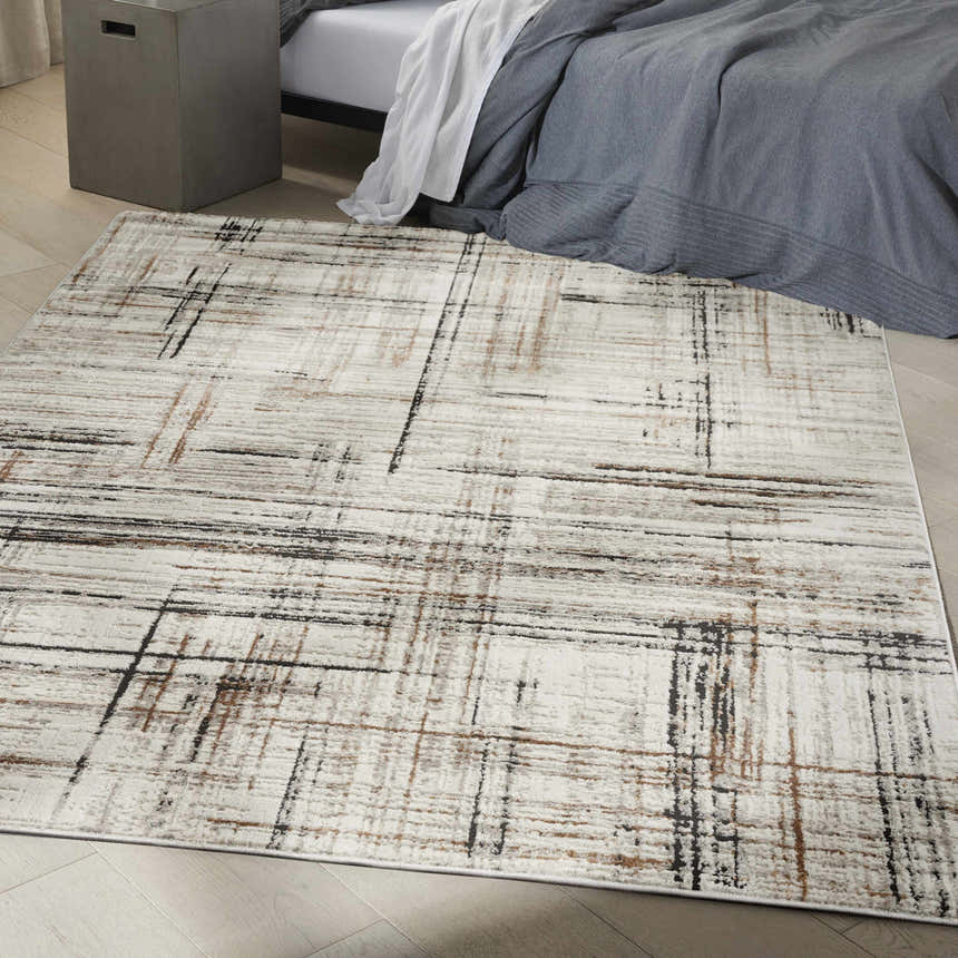 Bedroom scene with Calvin Klein CK029 Captivating Ivory Multicolor rug, gray bedding, and concrete side table. Modern style.