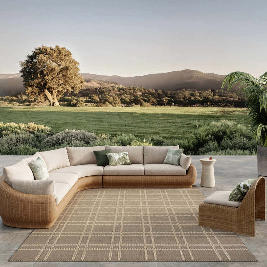 Outdoor patio scene with wicker furniture and Nourison Horizon Charcoal rug. Taupe tones and a relaxing, natural setting.