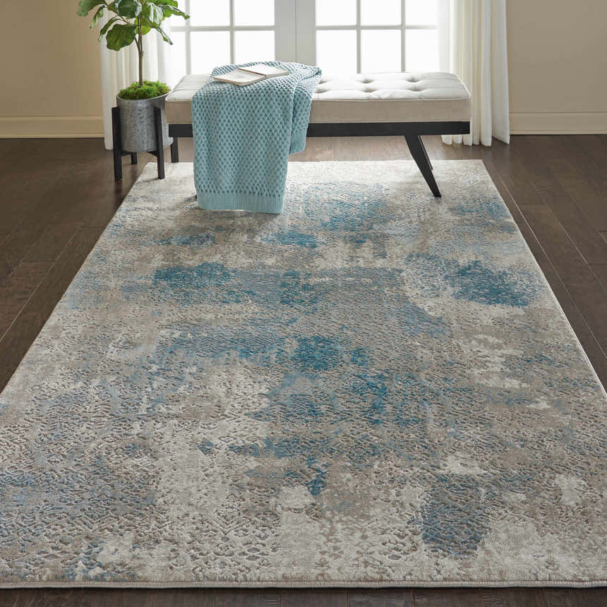 Room scene with Nourison Karma Ivory/Light Blue Rug. Vintage rug under bench with blue throw in neutral room.