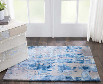 Bright room with a Nourison Prismatic Blue Grey rug, wood floors, and a modern accent table.