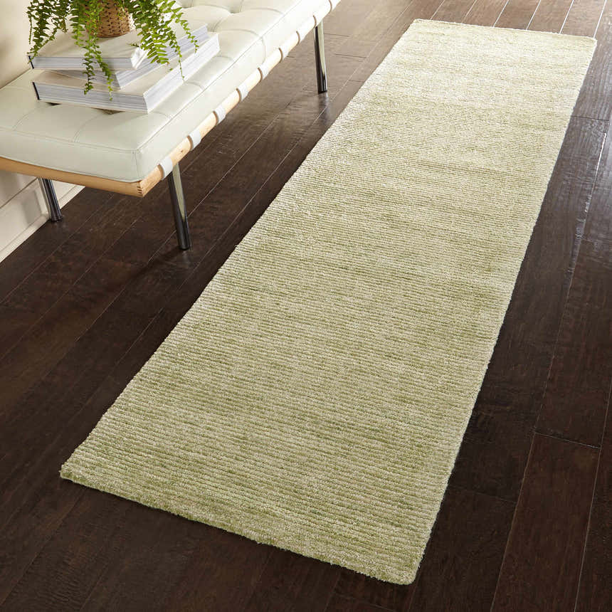Hallway scene with a Nourison Weston Citron runner rug on dark wood floors, next to a white leather bench.