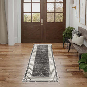 Entryway with wood floors and a Nourison Desire Charcoal Silver rug, bench, plants, and double doors.