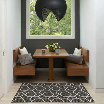 Modern dining nook with wood benches and a black geometric Nourison Horizon area rug.