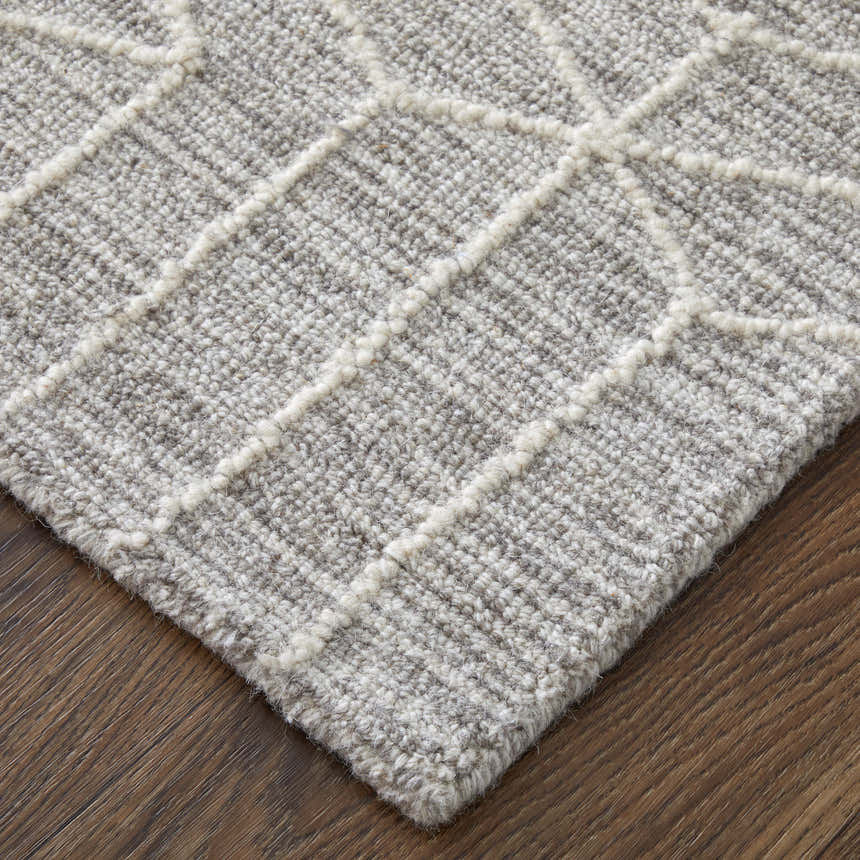 Close-up of Feizy Emerson rug. Gray wool rug with ivory geometric diamond pattern. Hand-tufted texture. Corner