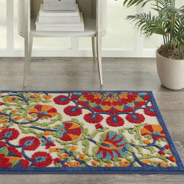 Entryway with a Nourison Aloha Red Multicolor rug, side table, and potted plant.