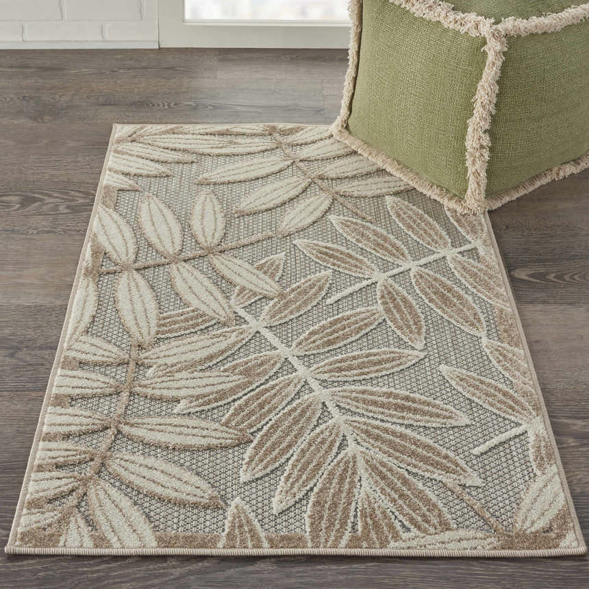 Styled Nourison Aloha Natural Tropical Area Rug. Close-up shows a leaf pattern in beige and brown on a gray background.