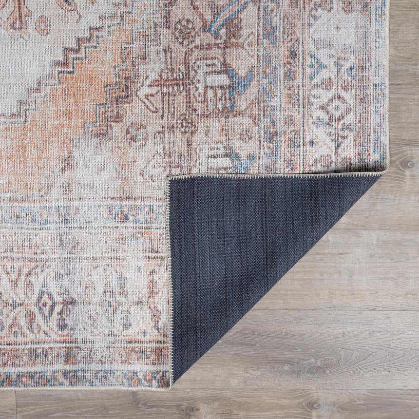 Close-up of Arncliffe Washable Area Rug showing its tan, brown, orange, and blue traditional pattern and blue backing. Fold