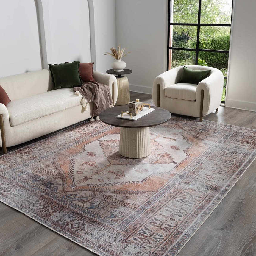Living room scene with a Bohemian Arncliffe Washable Area Rug in brown, orange, and slate. Sofa, chair, and round coffee table. Roomscene-Rectangle