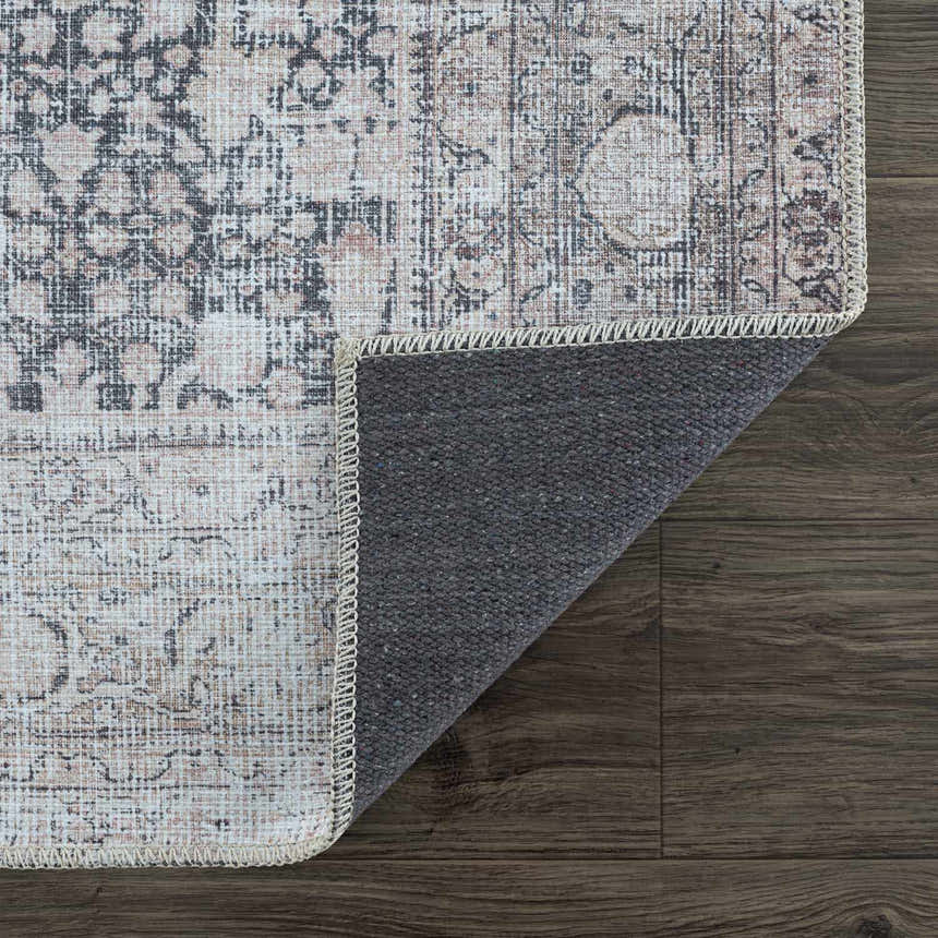 Close-up of the Hedda Boutique Washable Rug showing its dark gray, nutmeg, and gray vintage-style pattern and texture. Fold