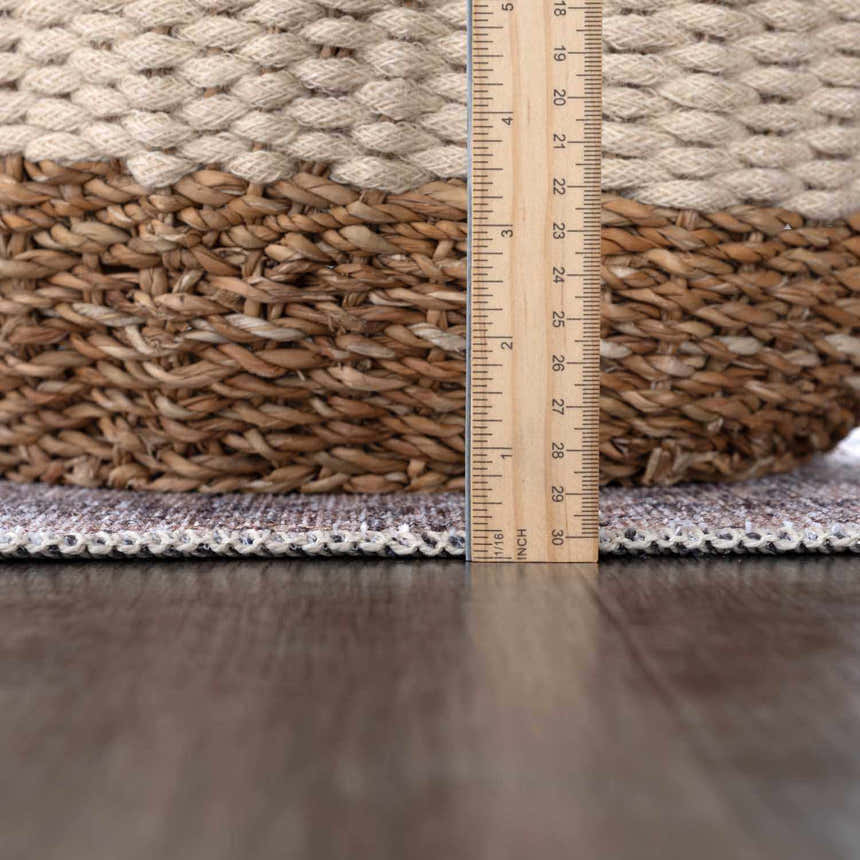 Close-up of the Hedda Boutique Washable Rug showing its thickness with a ruler, next to a woven basket. Pile